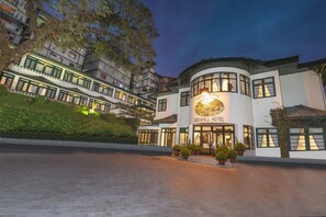 Un hotel de estilo arquitectónico tradicional, con varios pisos y una entrada destacada con un letrero.