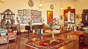 A spacious room with a grand piano, multiple framed pictures on the walls, and a variety of seating arrangements including sofas and chairs. - The Elgin Nor-Khill - A Heritage Hotel & Spa (Gangtok)