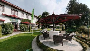 A hotel courtyard with outdoor seating, a flag, and a building with a red roof. - The Elgin Nor-Khill - A Heritage Hotel & Spa (Gangtok)