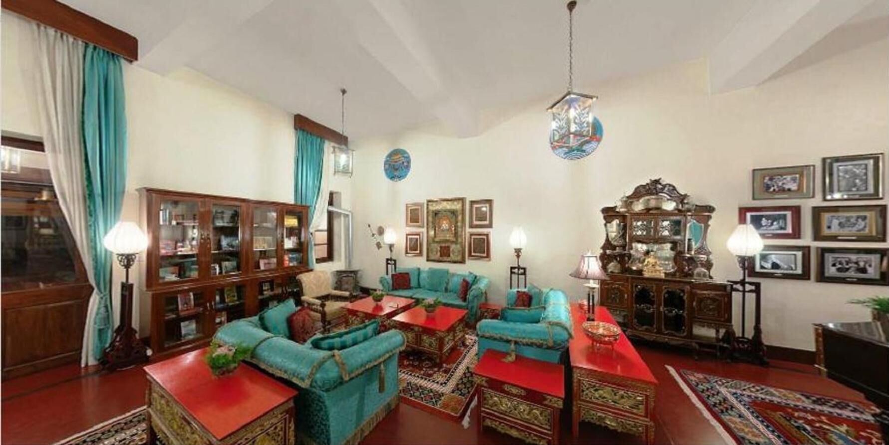 A traditional living room with a fireplace, wooden furniture, and a red carpet.