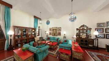 A traditional living room with a fireplace, wooden furniture, and a red carpet.