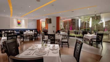Un restaurante con varias mesas para comer, cada una con manteles blancos, platos y cubiertos.