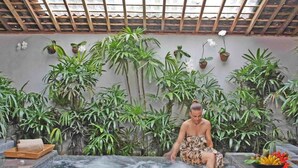Zona de spa con bañera de hidromasaje rodeada de exuberante follaje y plantas en macetas.