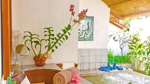 Un baño con bañera, toallas, espejo y una planta en maceta.
