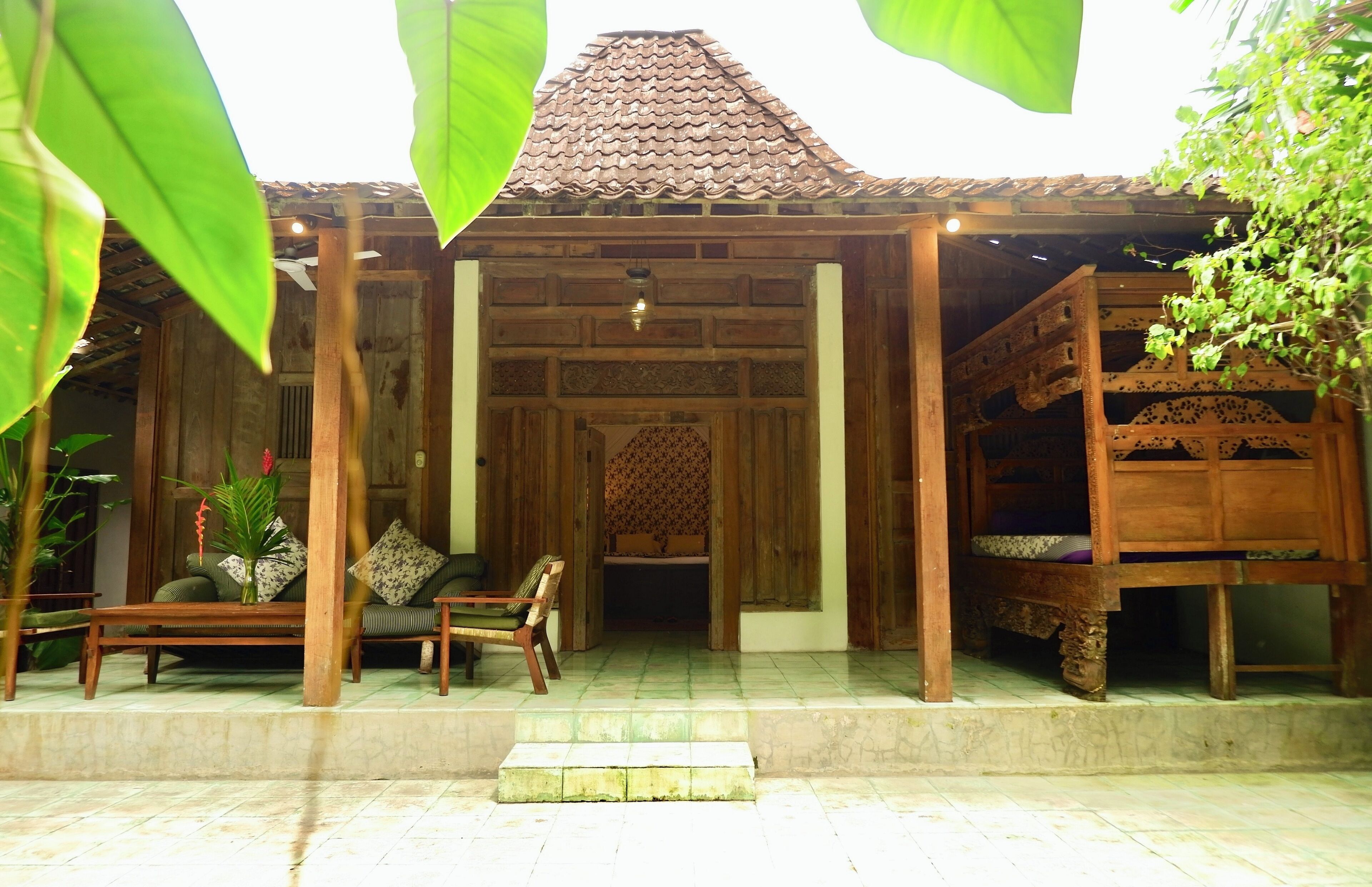 A wooden structure with a tiled roof, a bench, and a sofa with cushions.