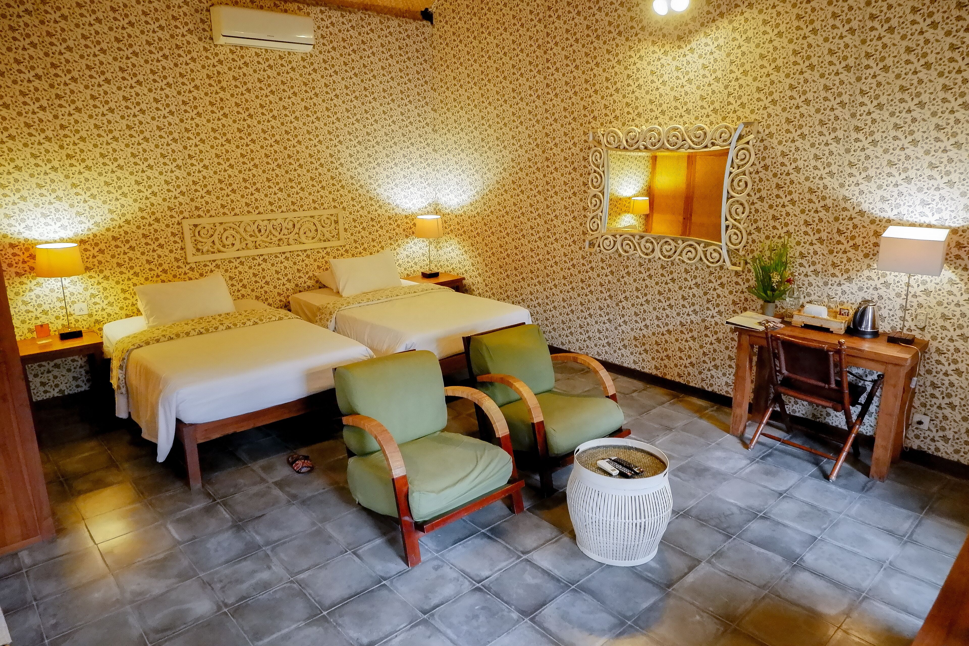 Une chambre d’hôtel avec deux lits, un bureau, une chaise et une corbeille à déchets.