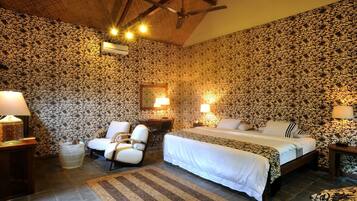 A bedroom with a bed, two bedside tables, a chair, a desk, and a mirror.