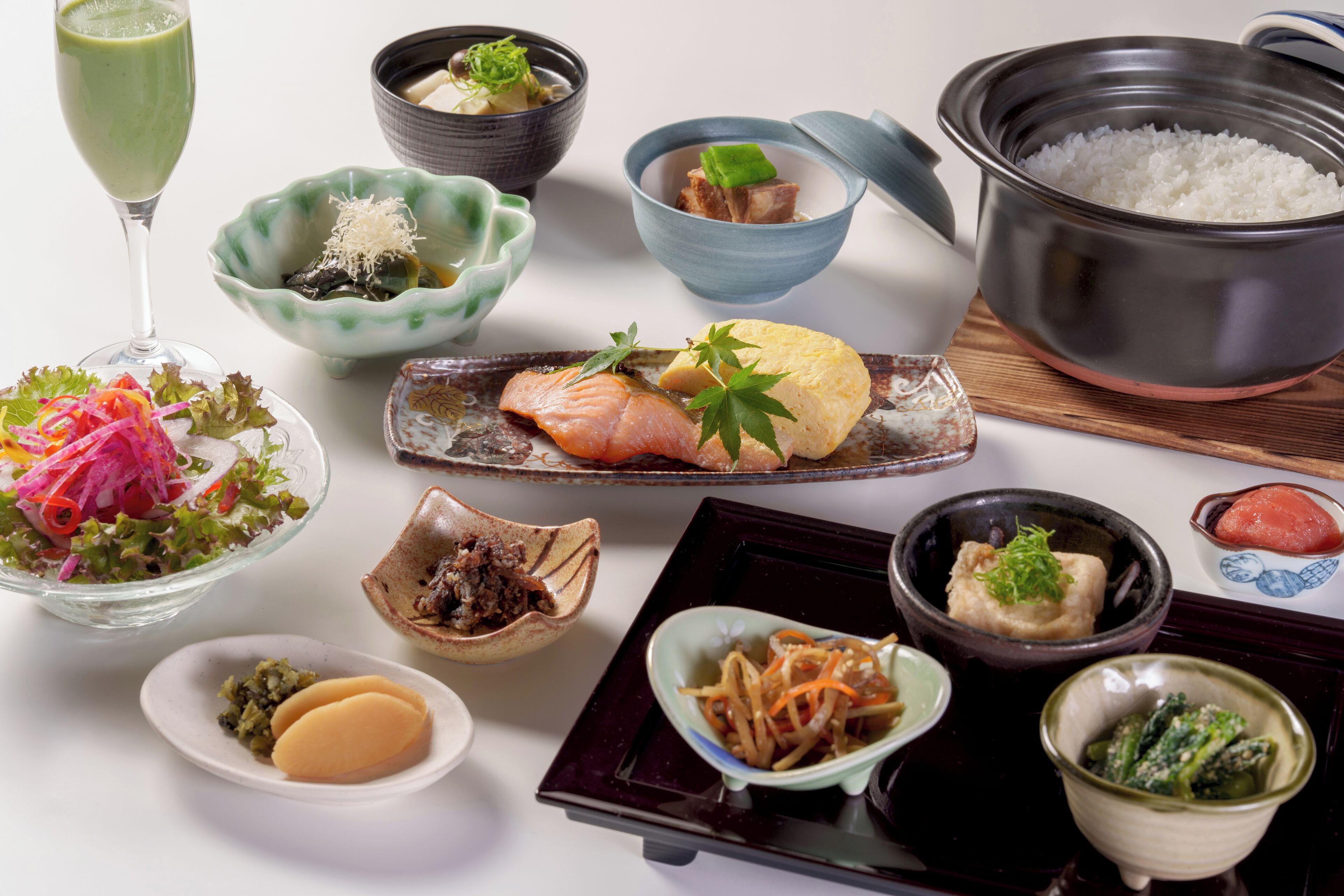 A variety of Japanese dishes including sushi, sashimi, and a pot of rice.