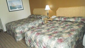 A hotel room with two beds, a nightstand with a lamp, a framed picture on the wall, and a striped carpet. - Bayview inn (Orillia)