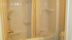 A bathroom with a bathtub, toilet, and a shower curtain. - Bayview inn (Orillia)