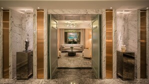 Een moderne lobby met marmeren wanden, een centrale zithoek en een kroonluchter.