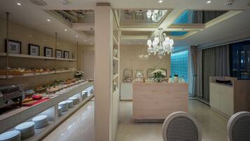 A hotel lobby with a buffet area, a reception desk, and a chandelier.
