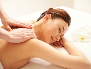 A person receiving a back massage in a room with a white bed and a single white flower on the bed. - Hotel Hanshin Osaka (Osaka)