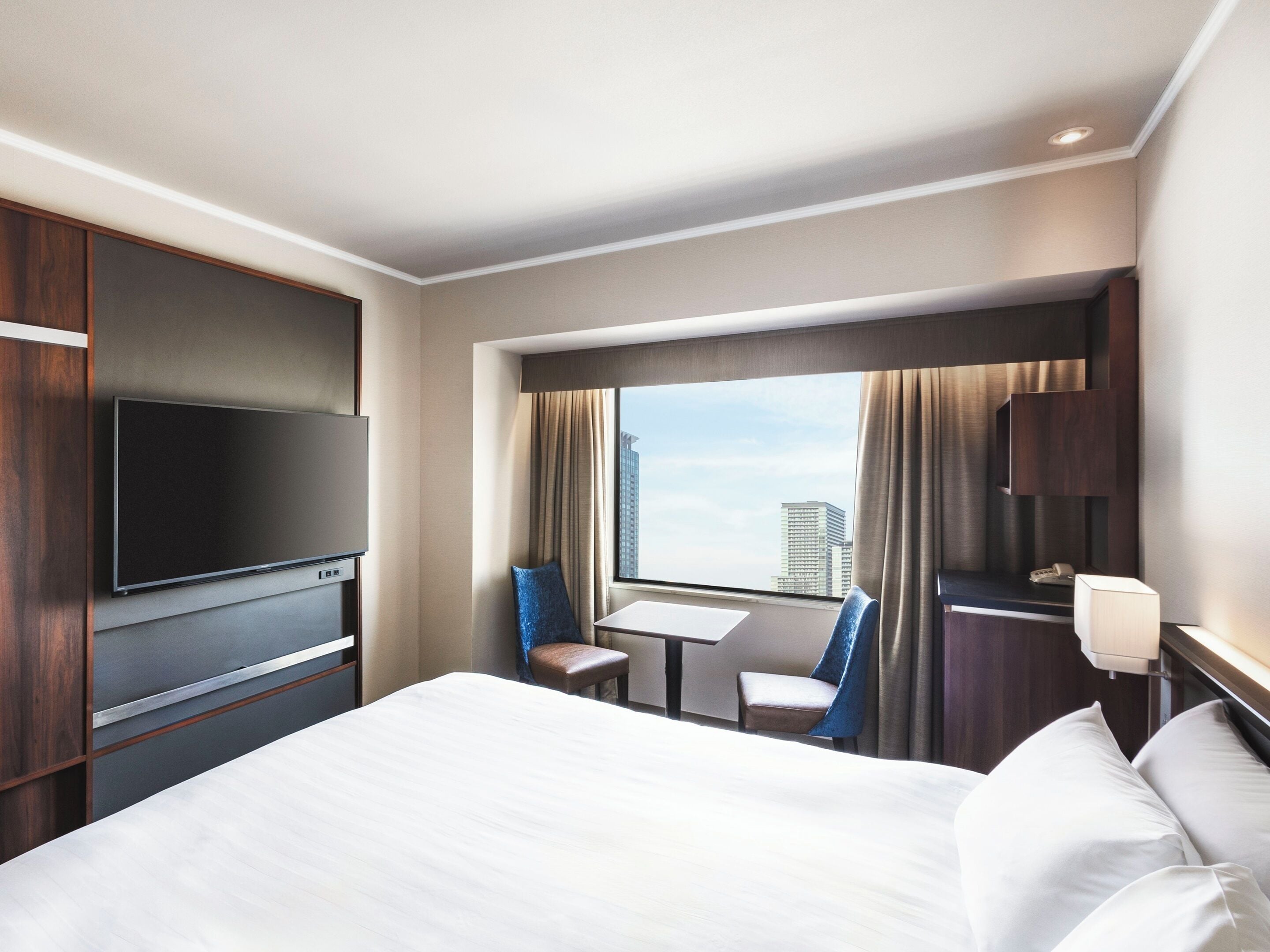 A hotel room with a bed, a TV, a desk, and a chair.