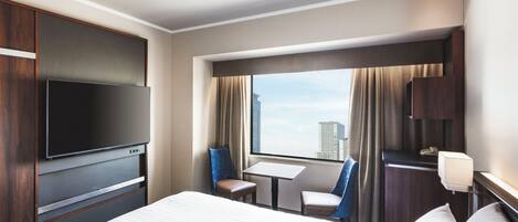 Een hotelkamer met een bed, een televisie, een bureau en een stoel.