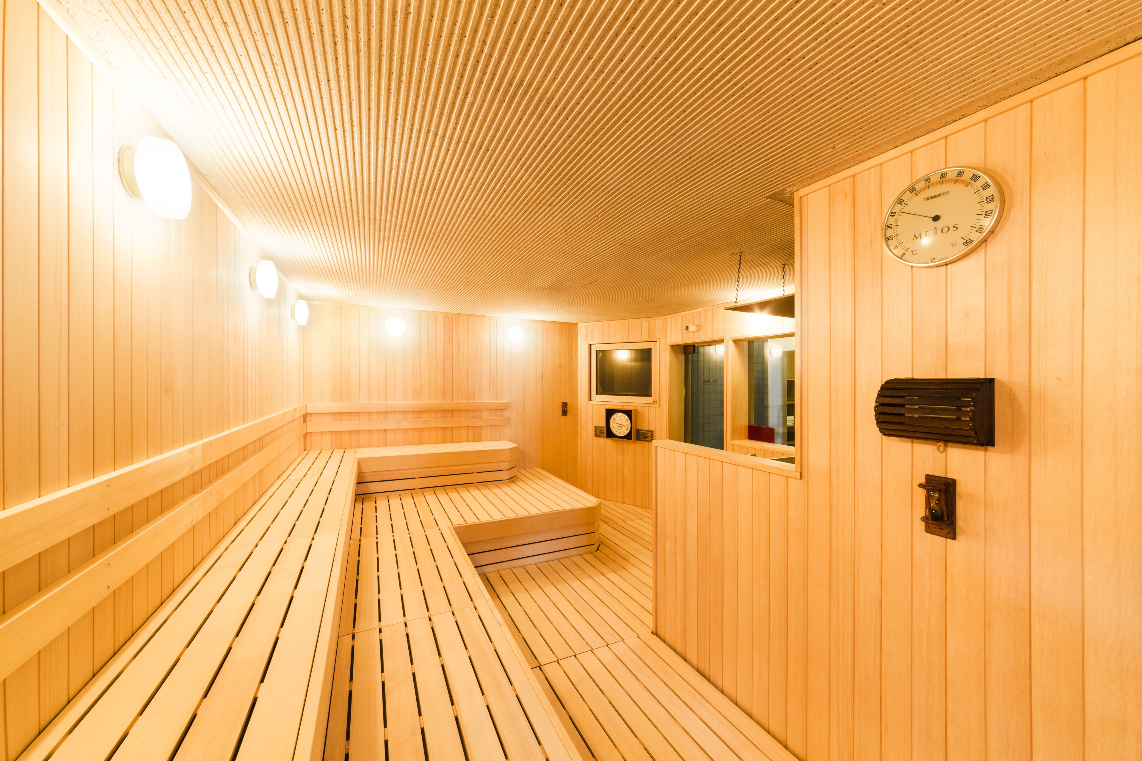 Una sauna de madera con bancos, un reloj y un calentador.