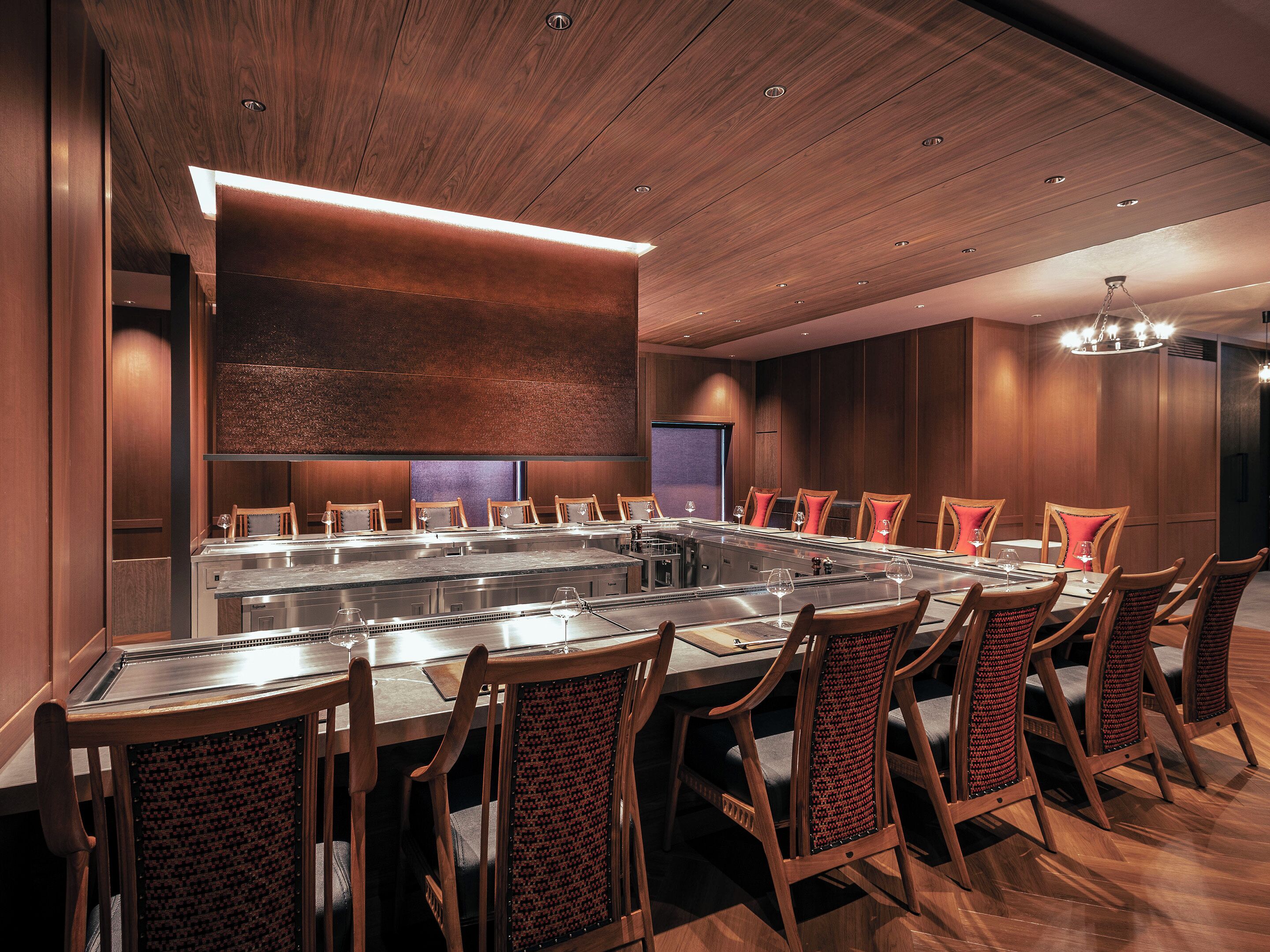 A conference room with a long table, multiple chairs, and a modern ceiling design.