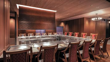 A conference room with a long table, multiple chairs, and a modern ceiling design.
