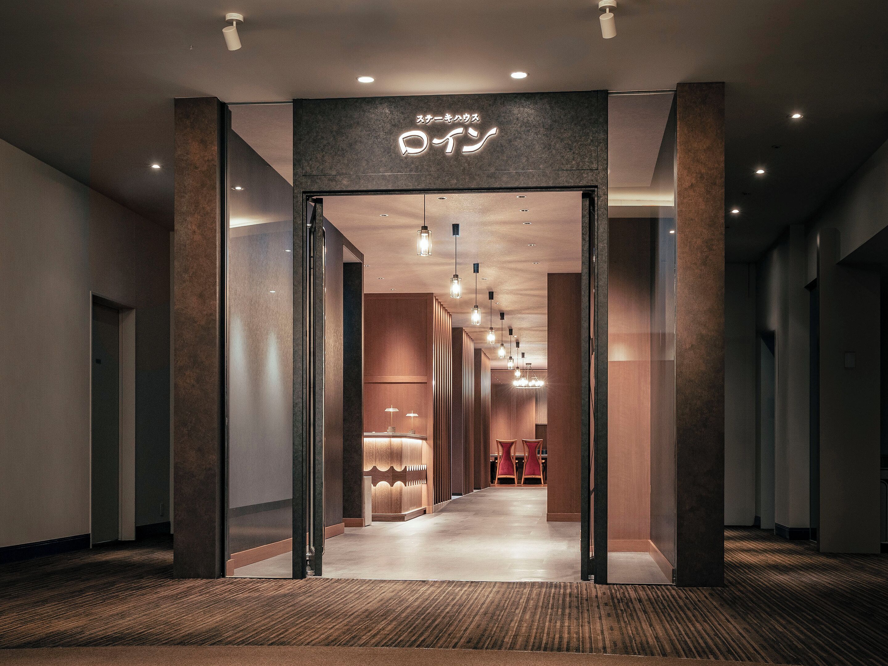 A hotel corridor with a reception desk, a seating area, and a sign above the entrance.