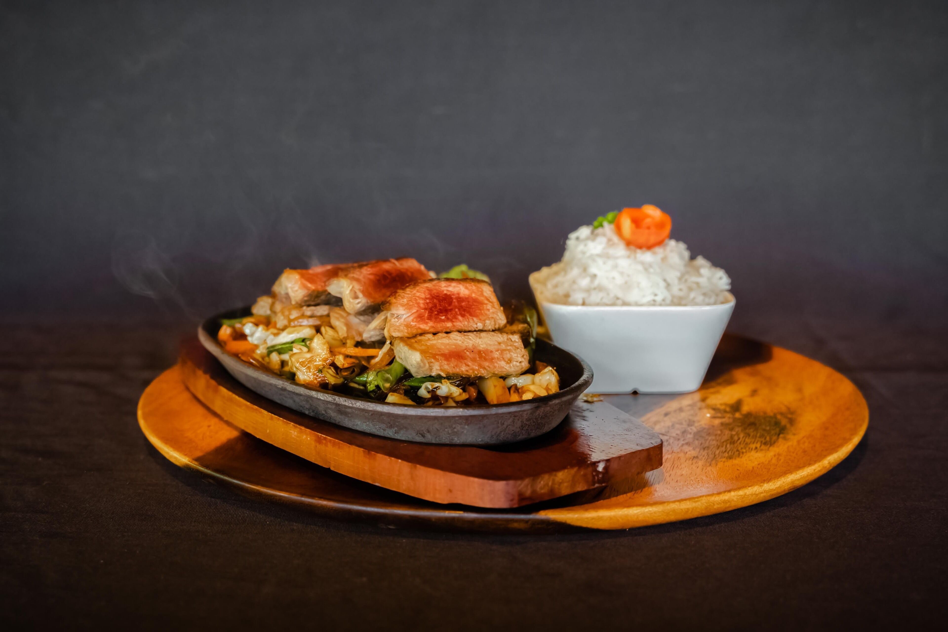 A dish with rice and a bowl of rice on a wooden plate.