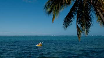 On aperçoit clairement une mer calme, et on distingue une personne pratiquant le kayak sur un kayak jaune.