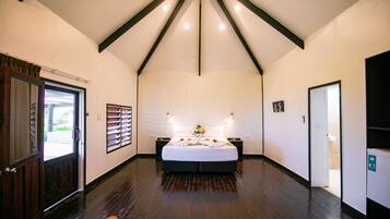 Una habitación amplia con una cama grande, suelo de madera y techo inclinado con vigas a la vista.