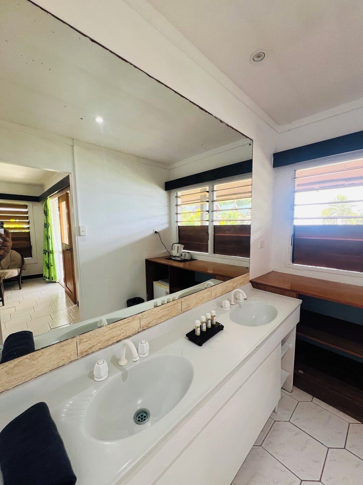 A bathroom with a large mirror, two sinks, and a vanity.