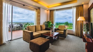 A spacious living room with a sofa, armchairs, and a coffee table, large windows with curtains, and a view of the outdoors. - Mondial Hotel Hue (Hue)
