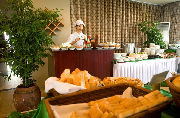 A buffet setup with various food items and a chef. - Mondial Hotel Hue (Hue)