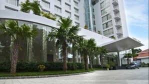 A modern hotel with a curved facade, multiple balconies, and a central cylindrical structure.