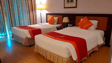 A hotel room with two beds, each with a red and white bedspread, a nightstand with a lamp, and a framed picture on the wall.