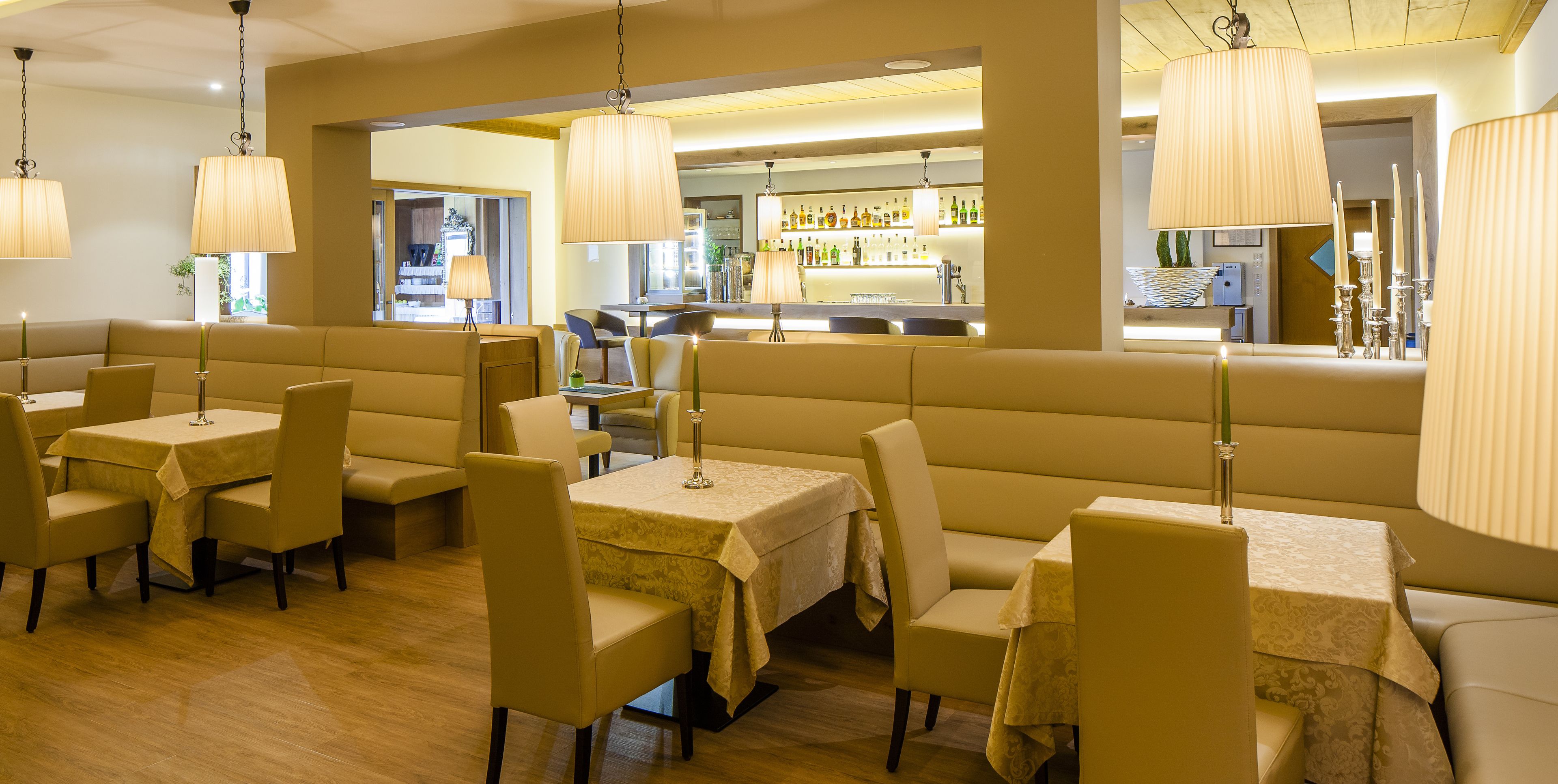 A restaurant with booths and tables, a bar area, and hanging lamps.