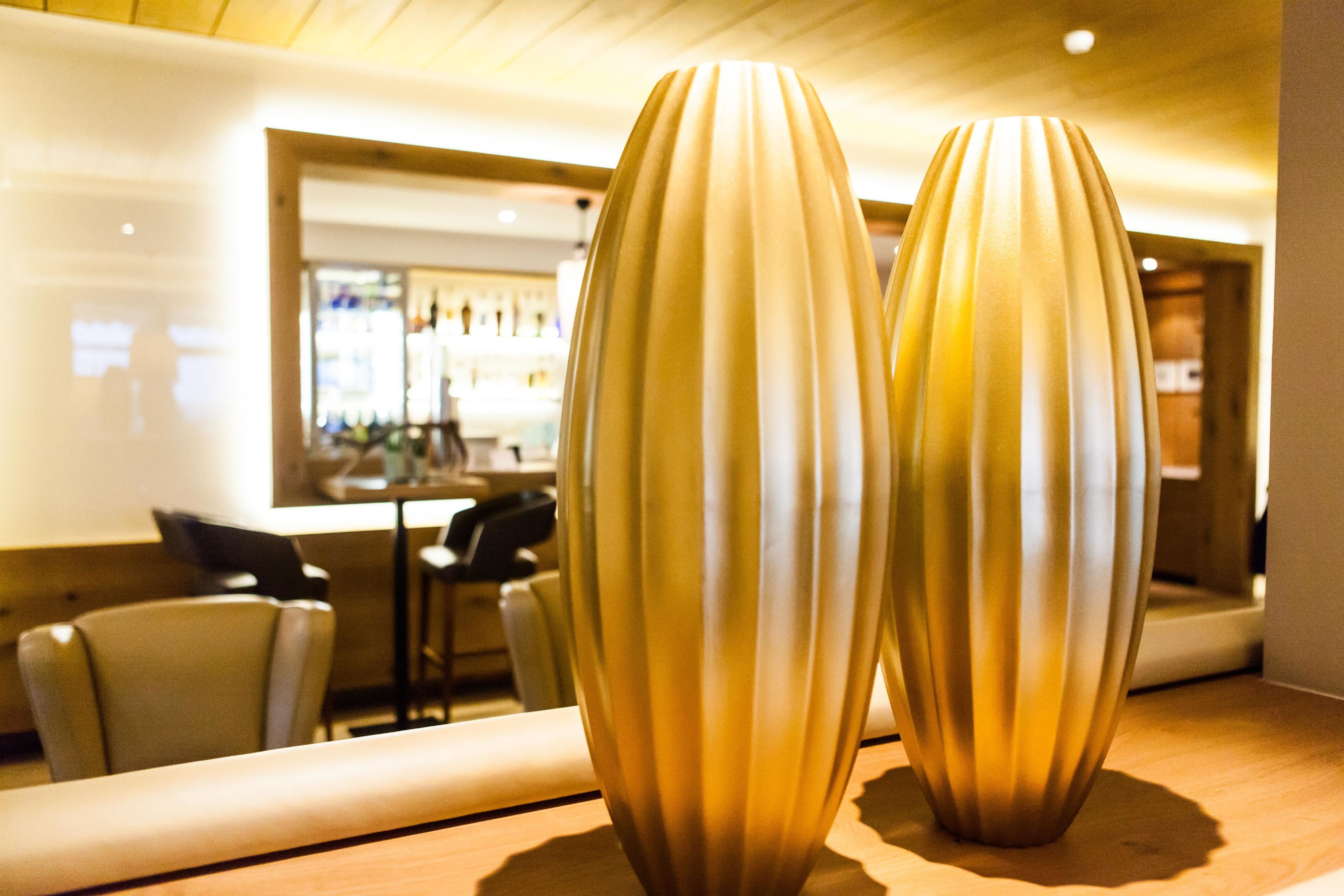 Two tall, slender vases on a wooden surface in a well-lit indoor setting.