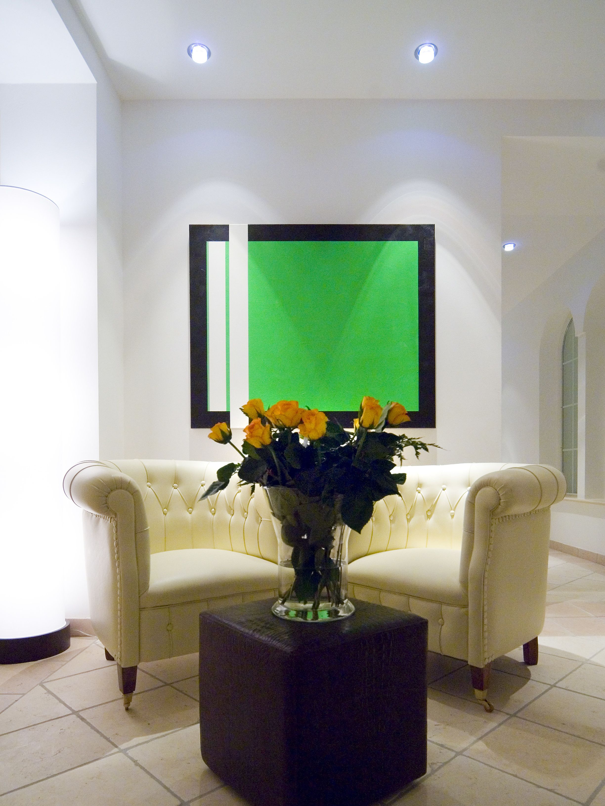 A room with a white sofa, a dark square coffee table, and a vase with flowers.