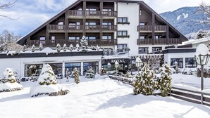 Et hotel med flere etager, altaner, et snedækket landskab og et bjerg i baggrunden.
