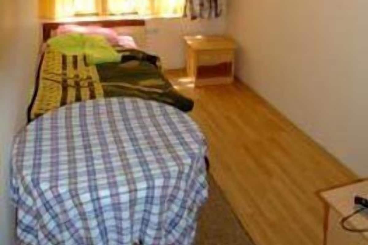 A room with a bed, a small table, and a window with curtains.