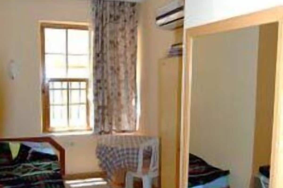 A small, compact room with a bed, a small table, and a window.