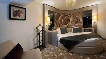 A modern hotel room with a curved bed, a large mirror, and a decorative wall.