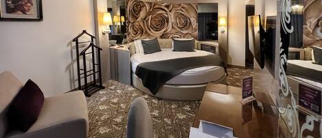 A hotel room with a bed, a chair, a desk, and a mirror.