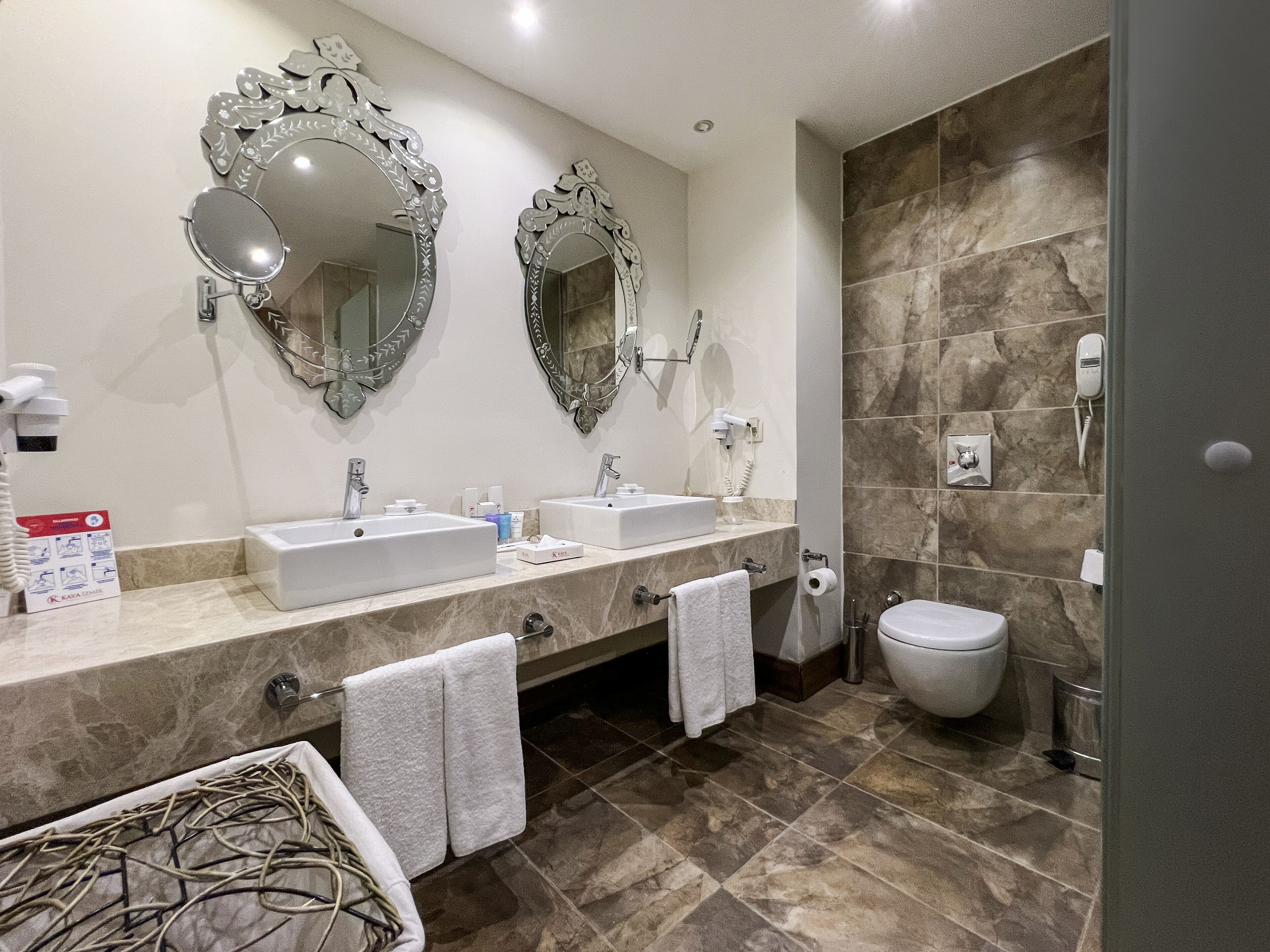 A bathroom with two sinks, a toilet, and two large mirrors.