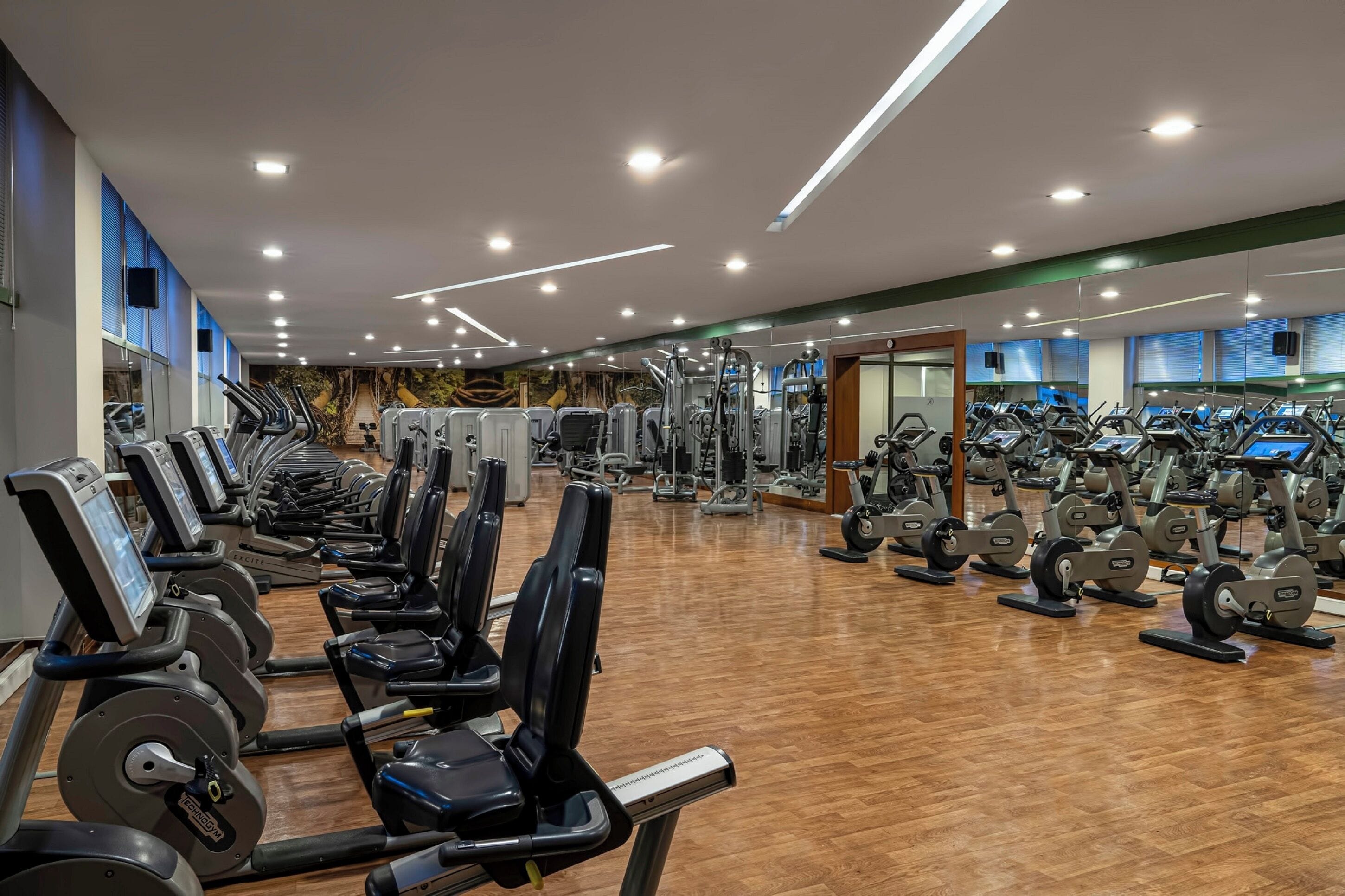 Une salle de sport équipée de plusieurs tapis de course, de machines de musculation et de miroirs.