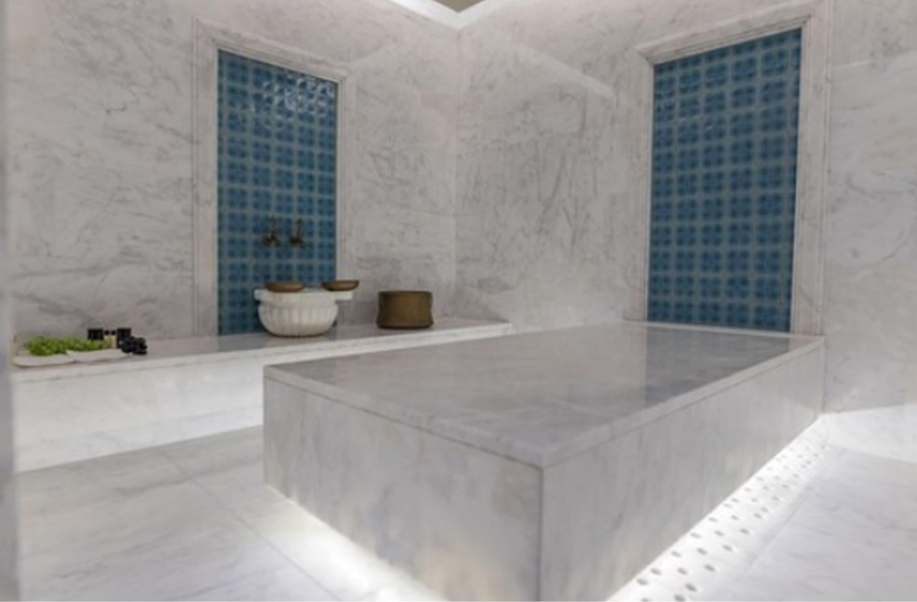 Ein modernes Badezimmer mit Marmorboden, einer freistehenden Badewanne und blauen Fliesen.