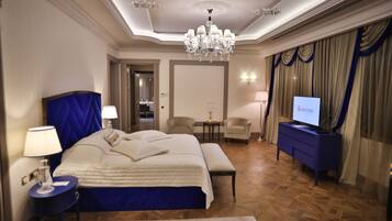 A hotel room with a large bed, a TV, a desk, and a chandelier.