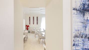 Un comedor moderno con mobiliario blanco y un cuadro abstracto grande en la pared.