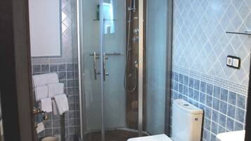 A bathroom with a glass-enclosed shower, a toilet, and a sink.