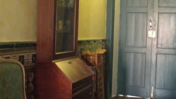 A room with a green upholstered chair, a wooden dresser, and a blue door.