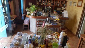 Um buffet de café da manhã com diversos itens de comida, incluindo pães, frios e acompanhamentos, além de bebidas.