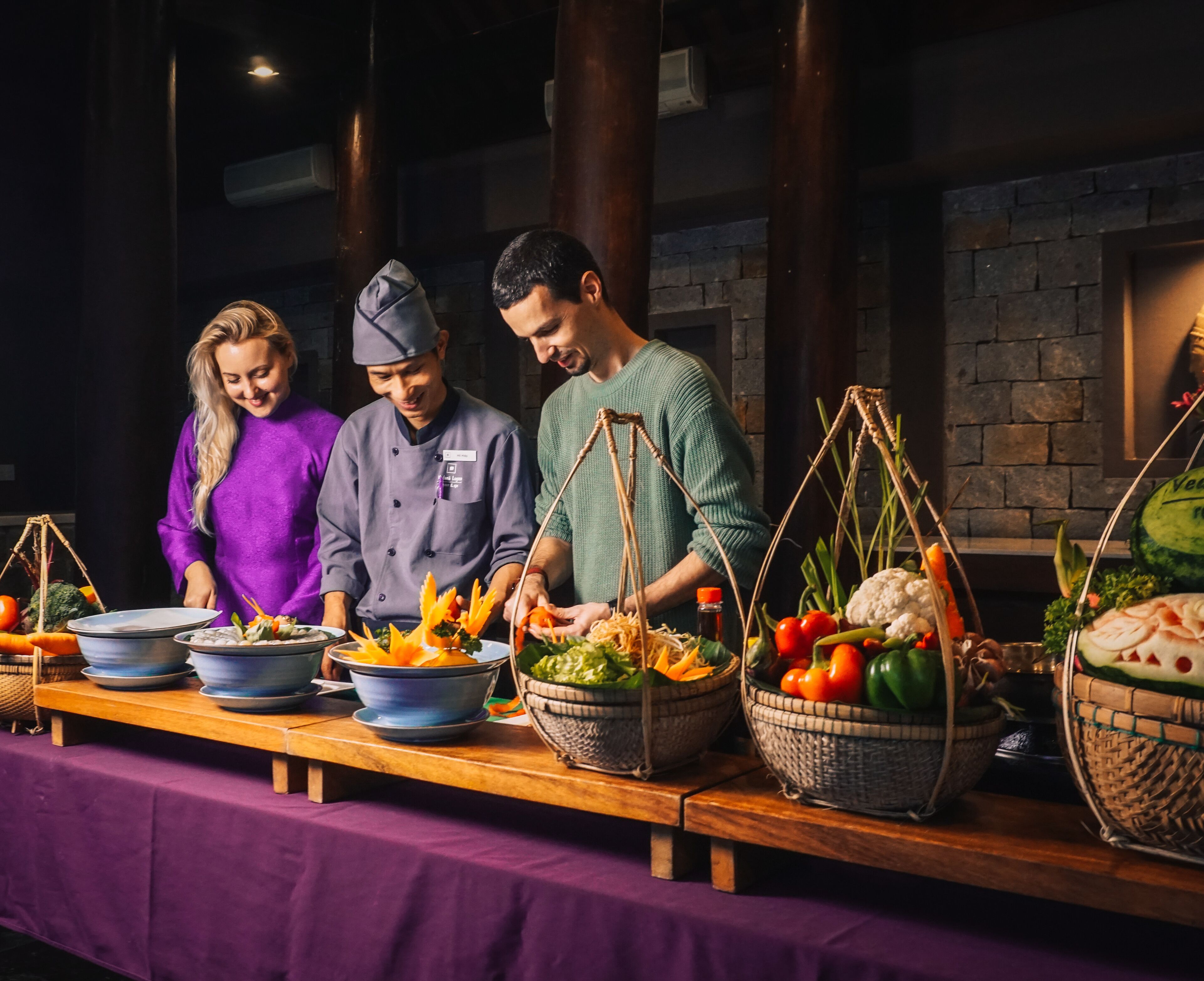 A buffet setup with chefs preparing food, surrounded by various dishes and fresh produce.