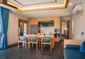 Eine moderne Küche mit Holzausstattung, ein Essbereich mit blauen Stühlen und ein Sofa.