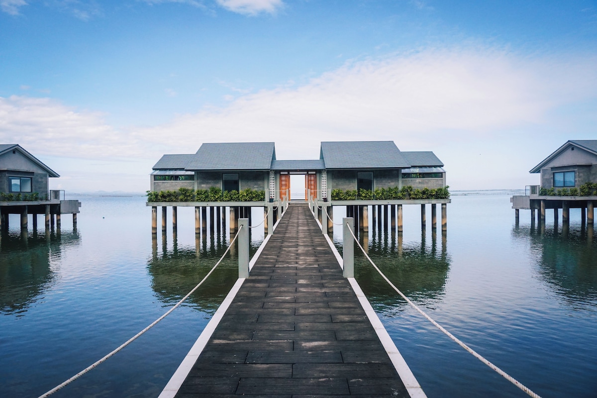 A wooden pier leading to overwater bungalows with a clear view of the sea.